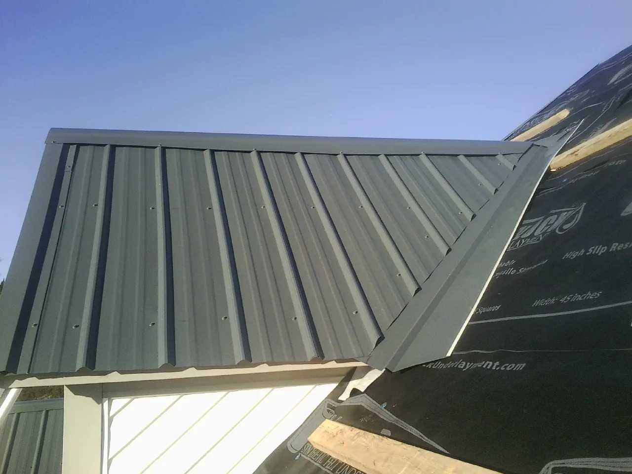 Gray metal roof panels going on over a garage gable in Randolph